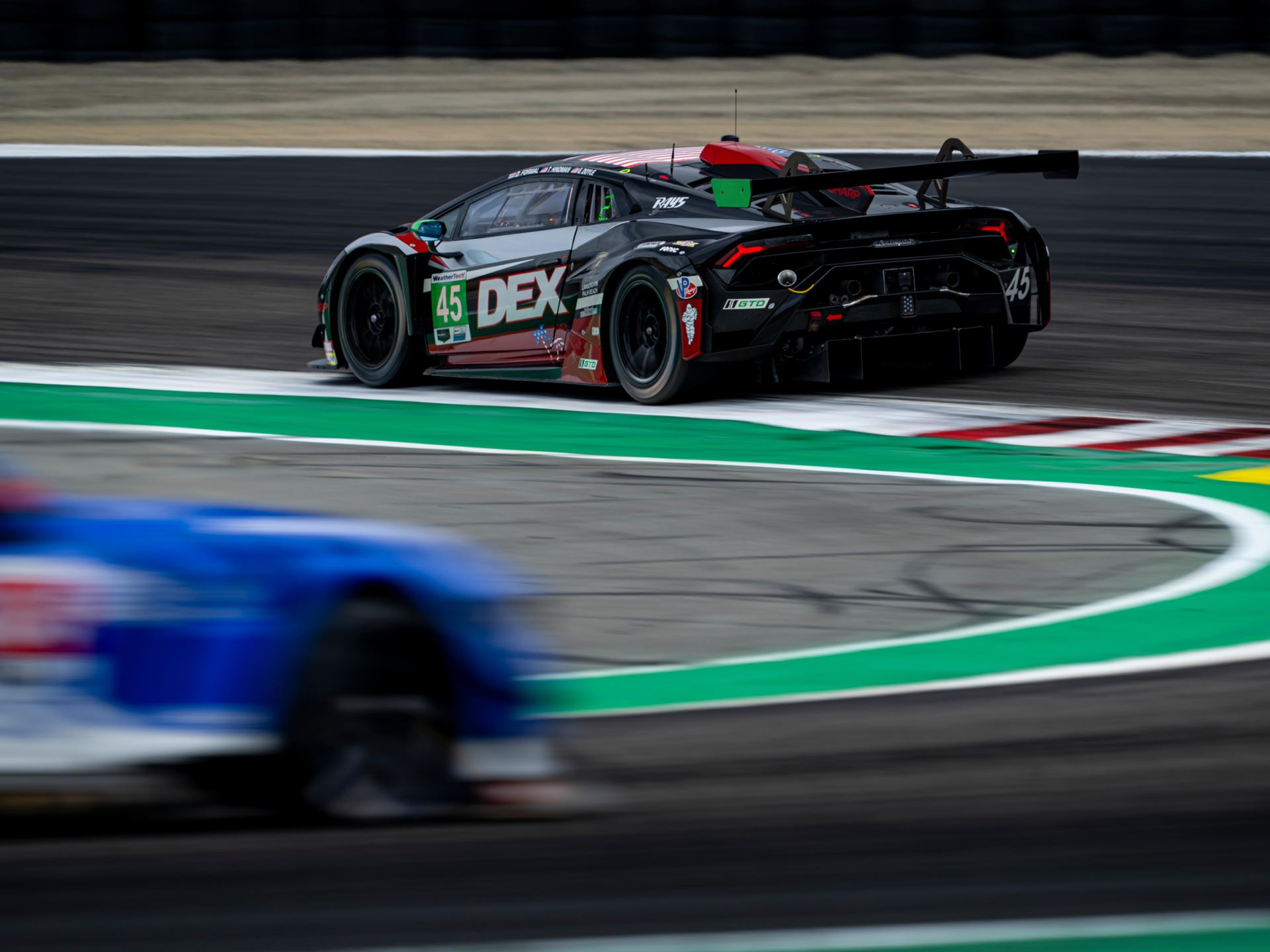 Huracán Gt3 Evo2 Wins At Laguna Seca While The Temerario Gt3 Posts Its Best Imsa Finish Yet 7 The #45 lamborghini huracán gt3 evo2 in black livery with red green and white accents speeding through a corner at laguna seca with visible rear wing diffuser and racing slicks