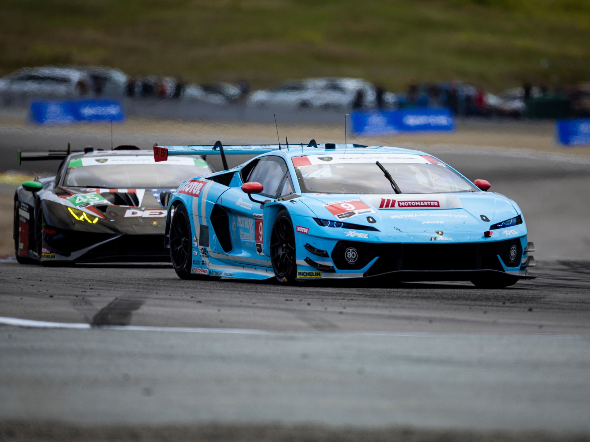 Huracán Gt3 Evo2 Wins At Laguna Seca While The Temerario Gt3 Posts Its Best Imsa Finish Yet 5 The #9 temerario gt3 in light blue leading the #45 huracán gt3 evo2 in black livery on track at laguna seca with spectators in the background